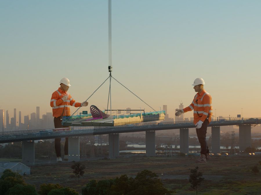 A giant construction worker moves a train station canopy into place.