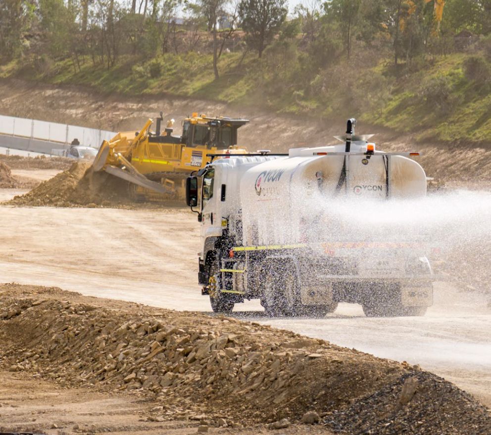 Truck spraying water on a haul road to manage dust