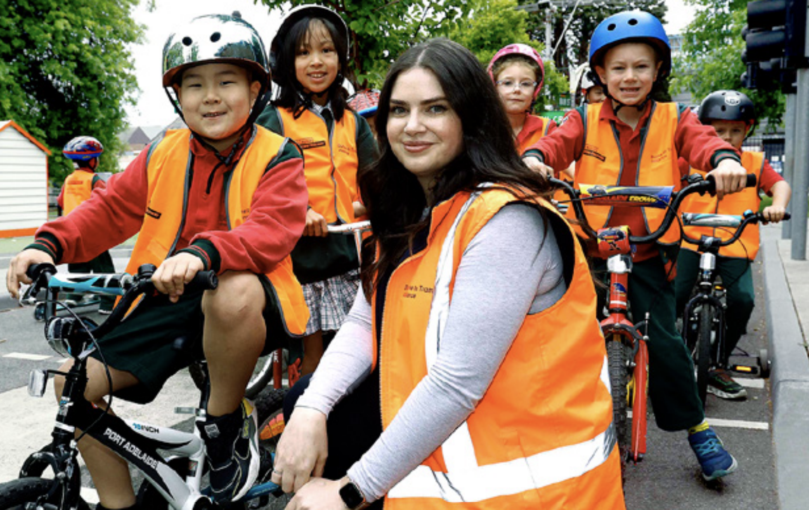 School children riding bicycles wearing helmets and high vis vests