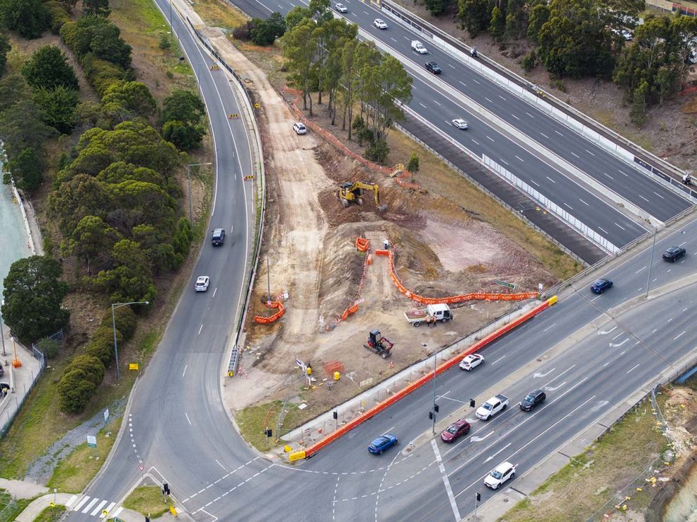 Crews working behind barriers to widen the freeway ramp