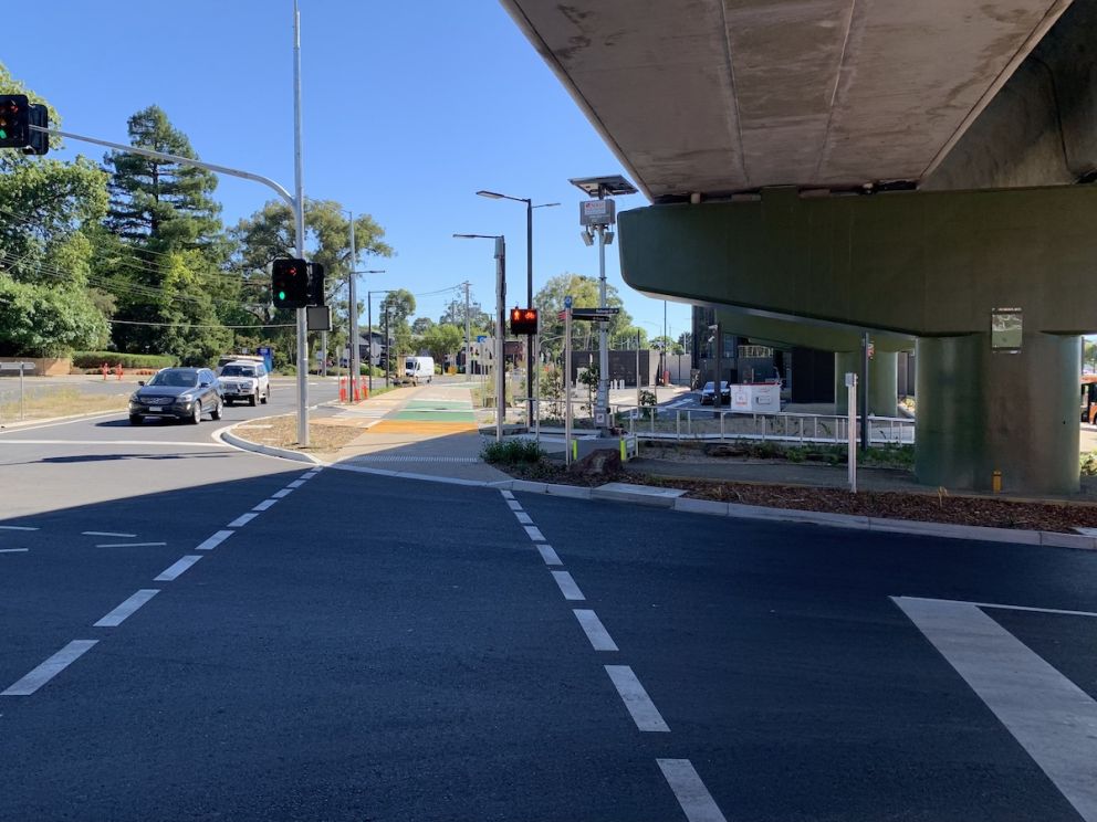 Pedestrian crossing alongside the elevated rail bridge.