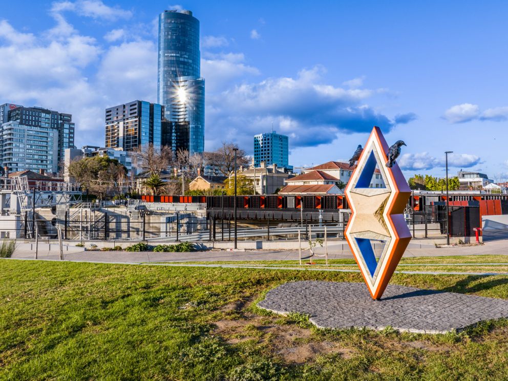 Abstract sculpture at park with train bridge in background