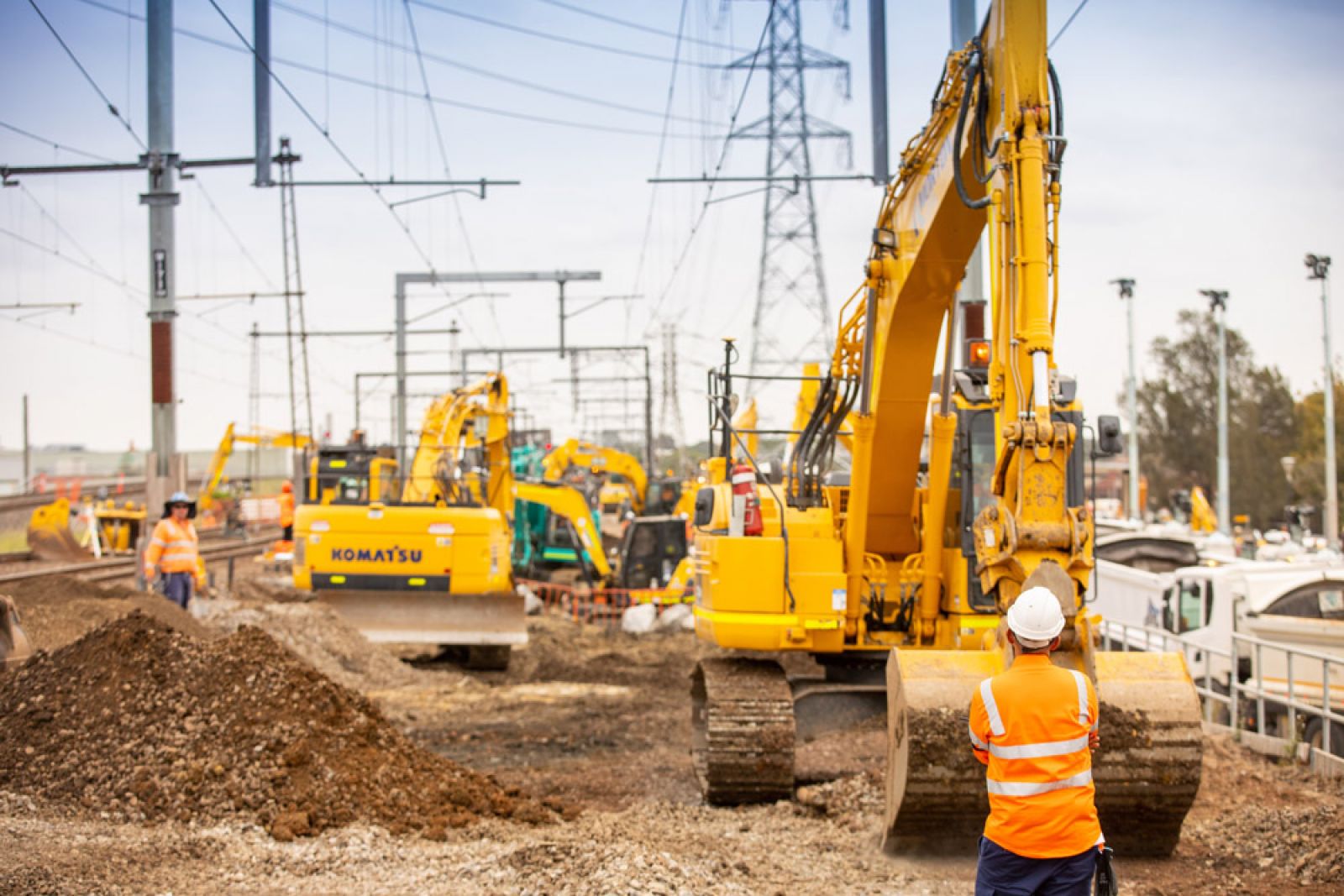 Spotters supervising earth moving equipment to avoid damage to items out of sight of the operator managing the excavator 