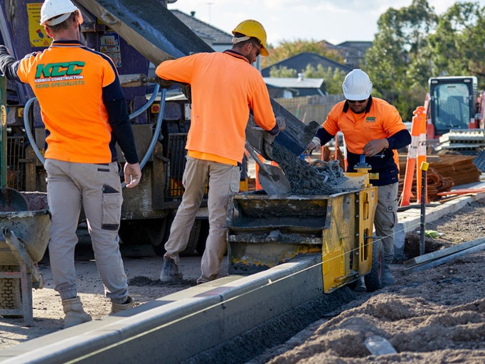 Image of concrete being poured by three construction workers