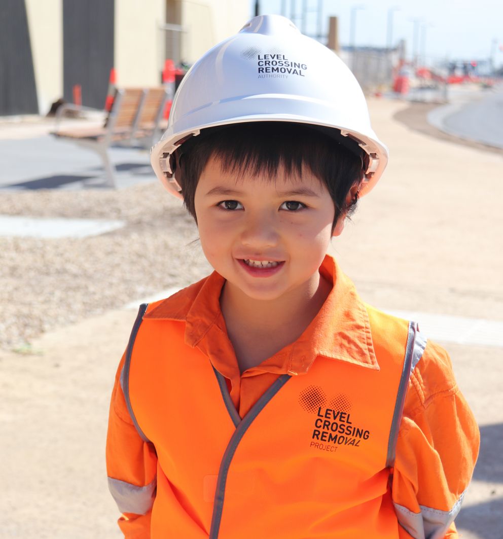 Kai, small boy smiling wearing hi-vis orange vest and hard hat.