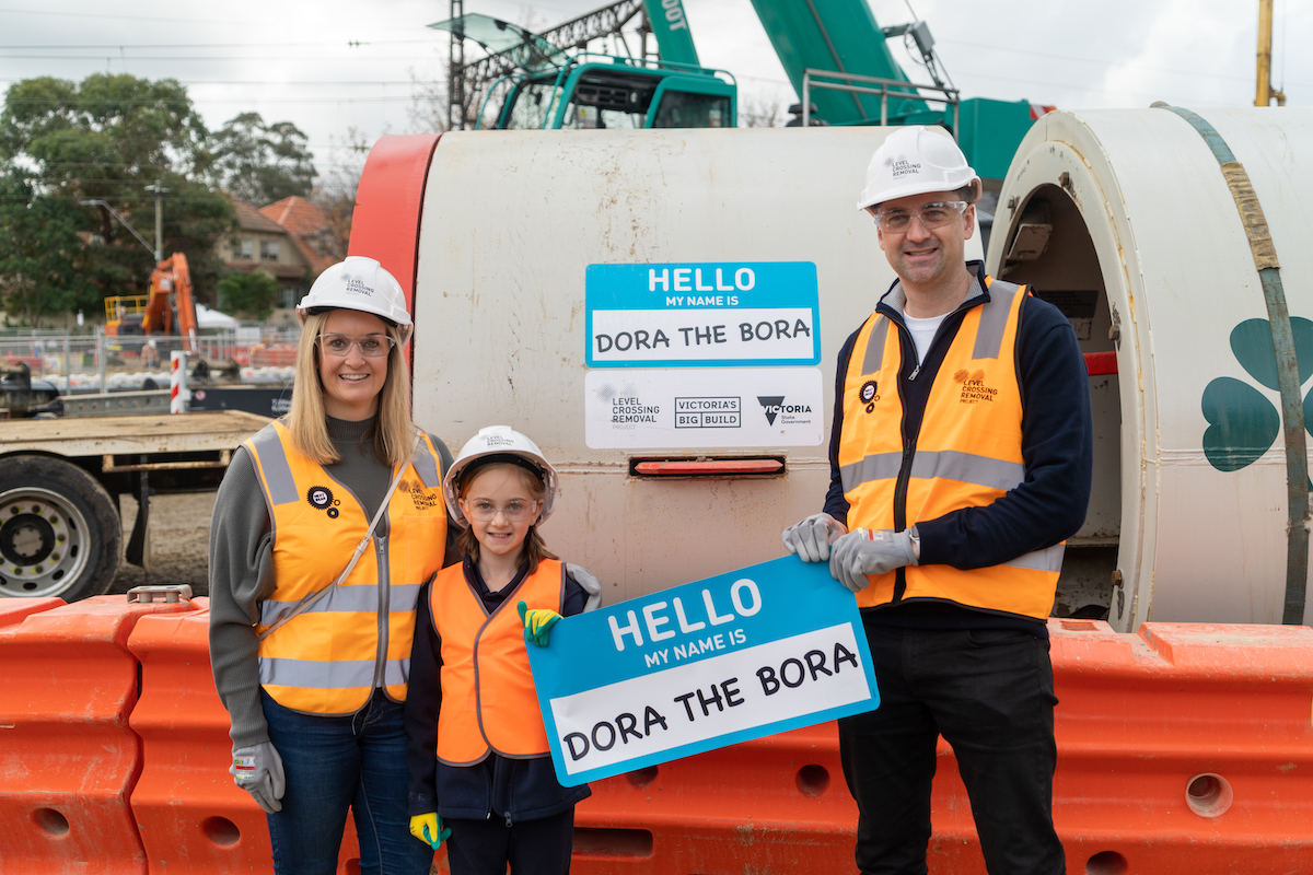 Grace from Surrey Hills Primary School Holding a sign saying 'Hi my name is Dora The Bora' in front of the Tunnel Boring Machine