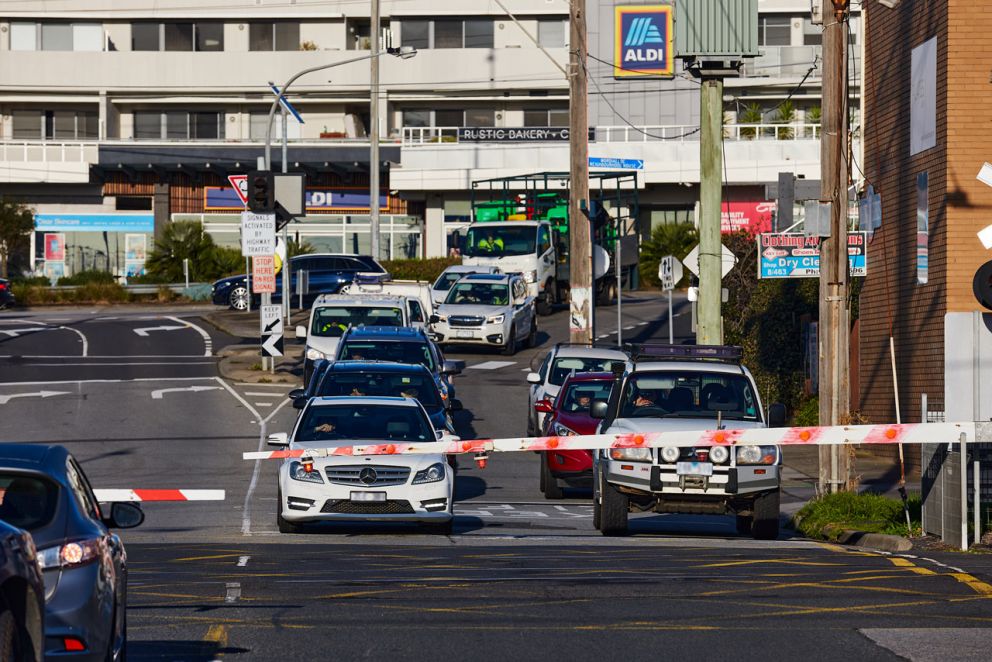Traffic waiting at the McDonald Street level crossing as a train is passing through