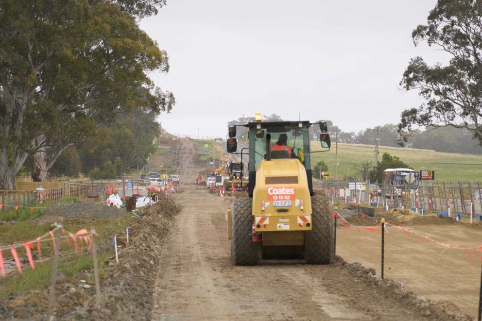 Works behind barriers to build the new westbound lanes and shared walking and cycling path on Hall Road