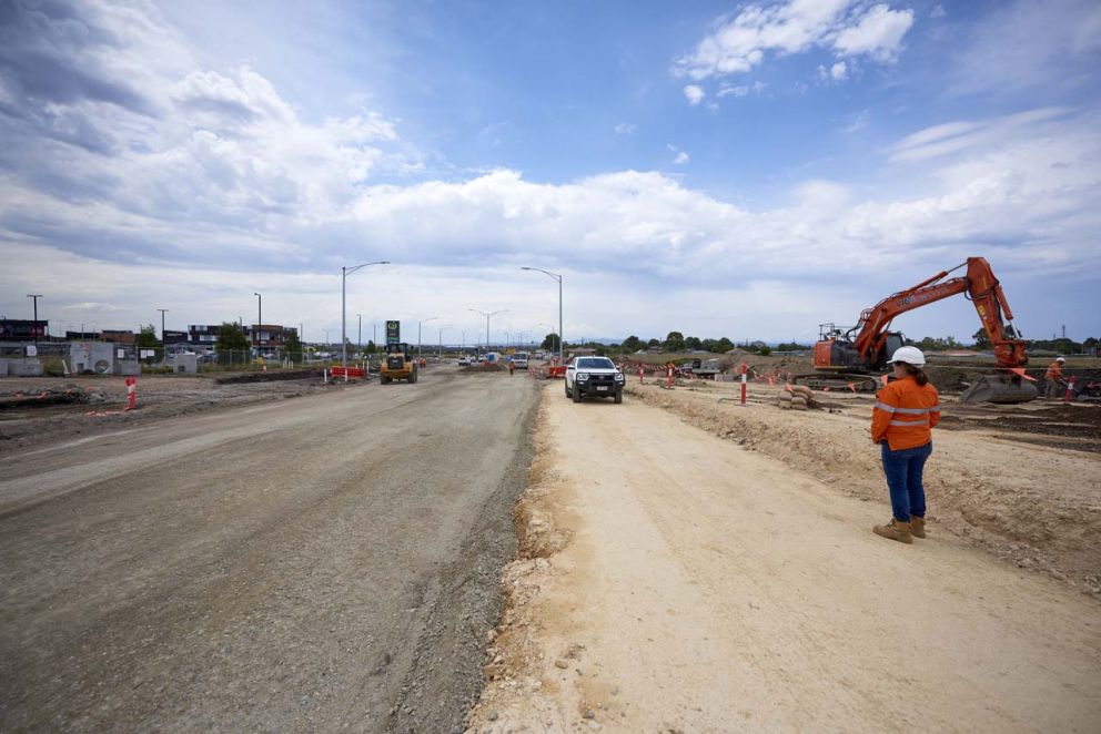 Compacting the new Evans Road leg of the intersection to place materials  