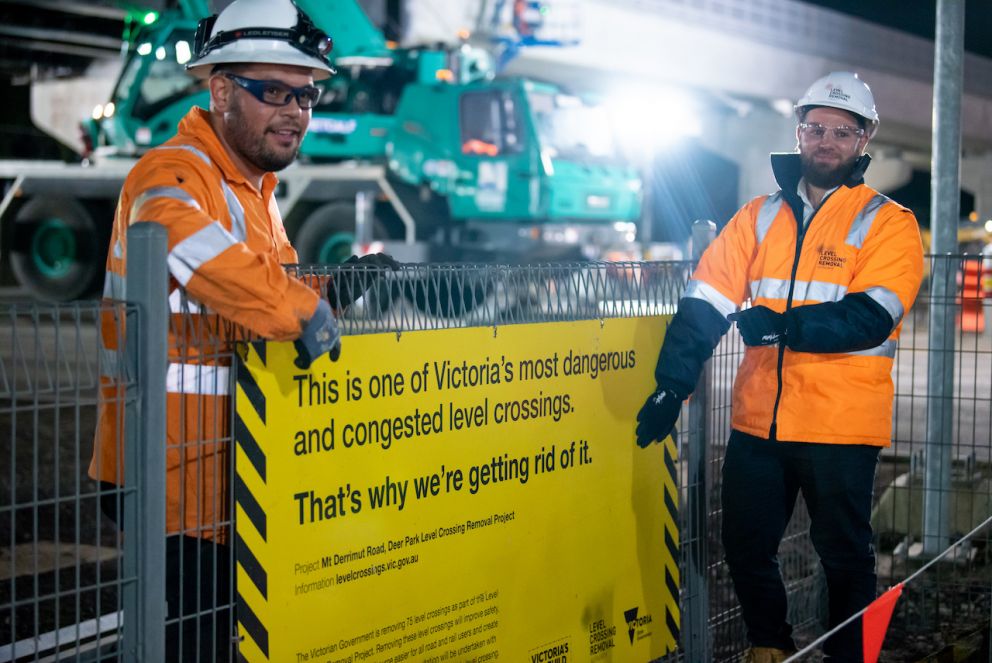 Construction workers with the Mt Derrimut Road level crossing removal sign