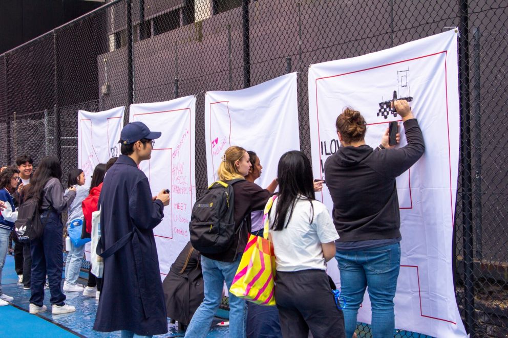 Image of a crowd of people making illustrations on four white panels.