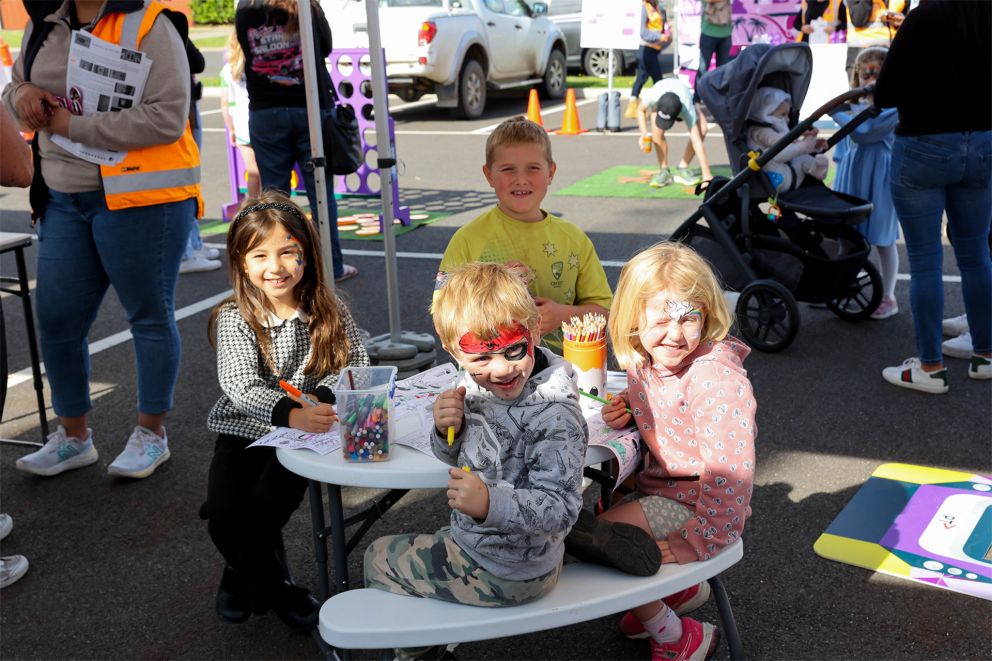 A group of children with their face painted colouring in at a table