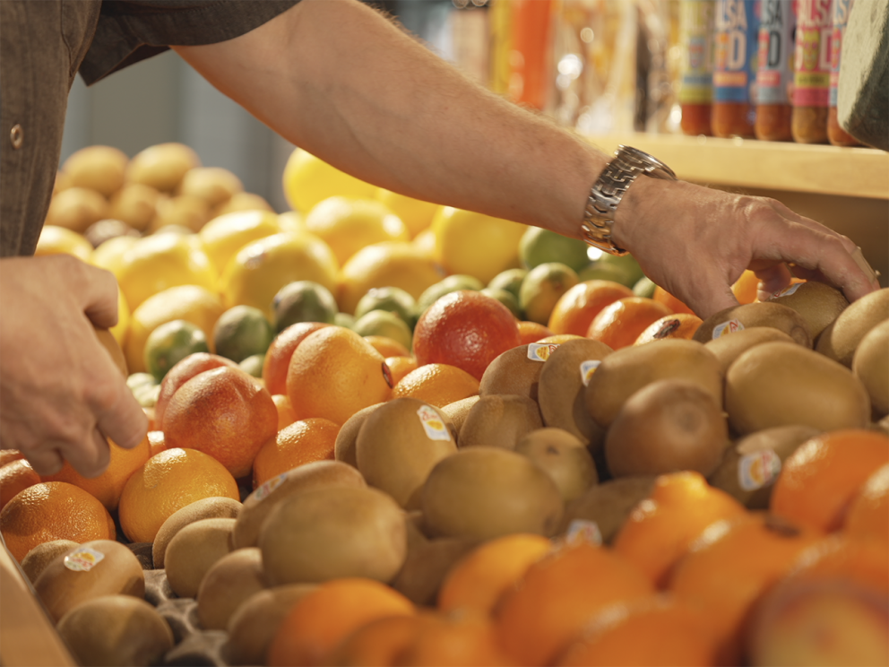 The Fruit Men Foodstore employee picking kiwi fruit from their range of fruits.