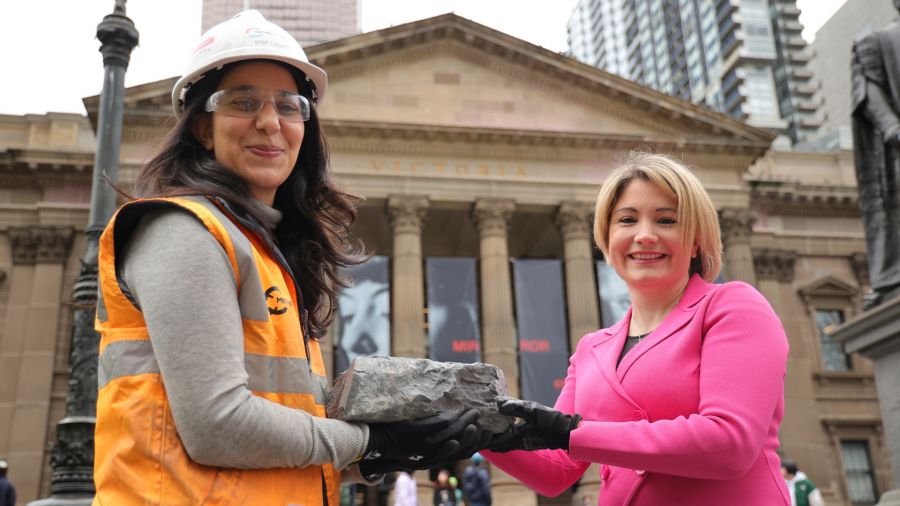 A engineer gifting a rock memento from the Metro Tunnel Project to a State Library Victoria representative.