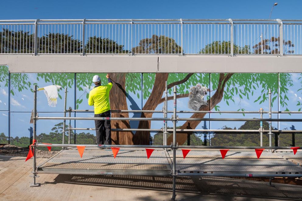 Artist Ervin Molnar painting a tree in to the bridge mural