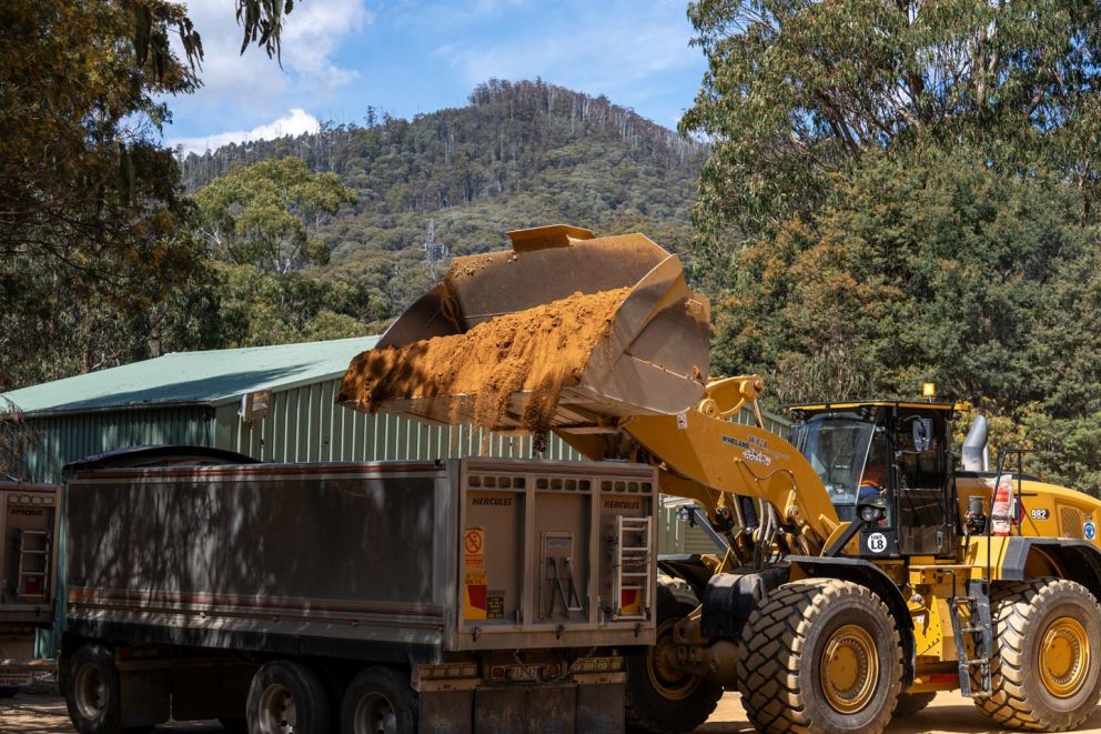 A bulldozer loads material into a Whelans truck