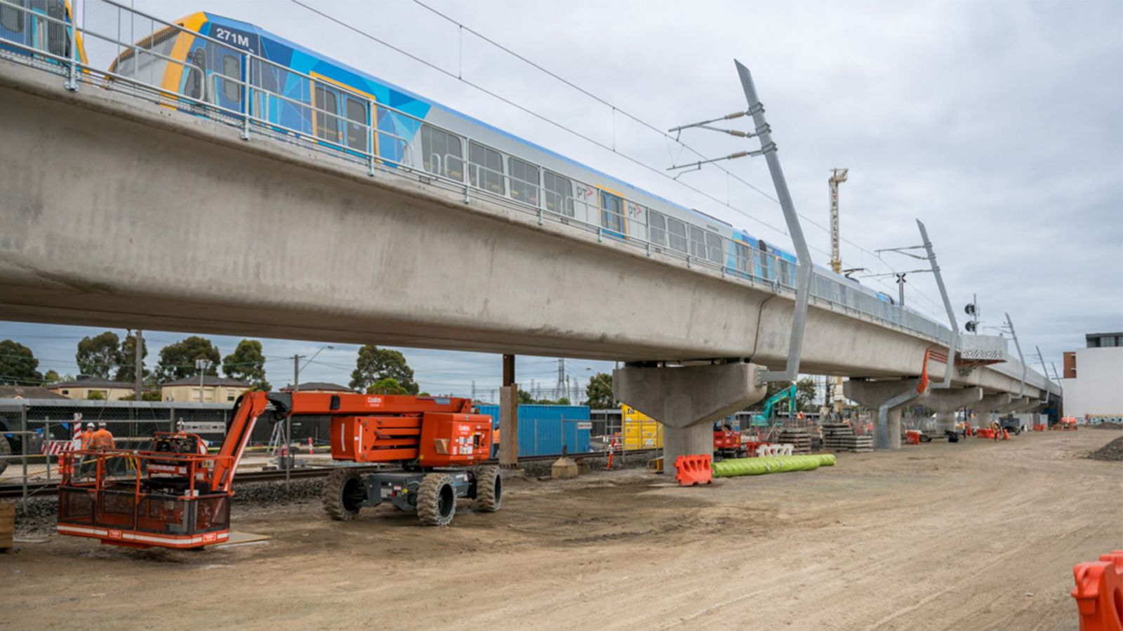 A train travels over a train bridge while construction continues underneath.