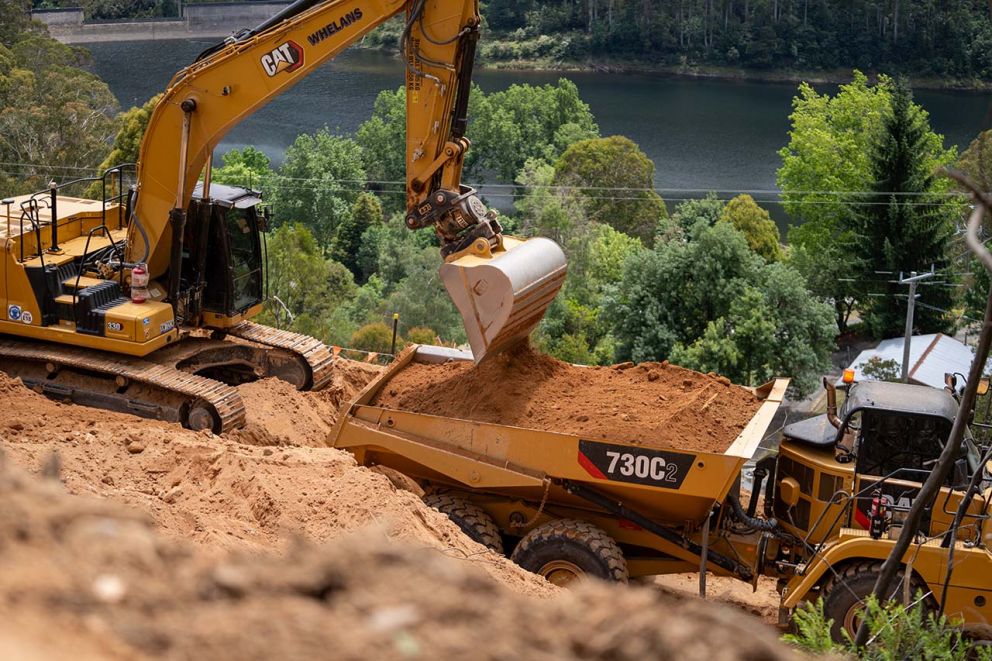 An excavator loading material into a moxy truck