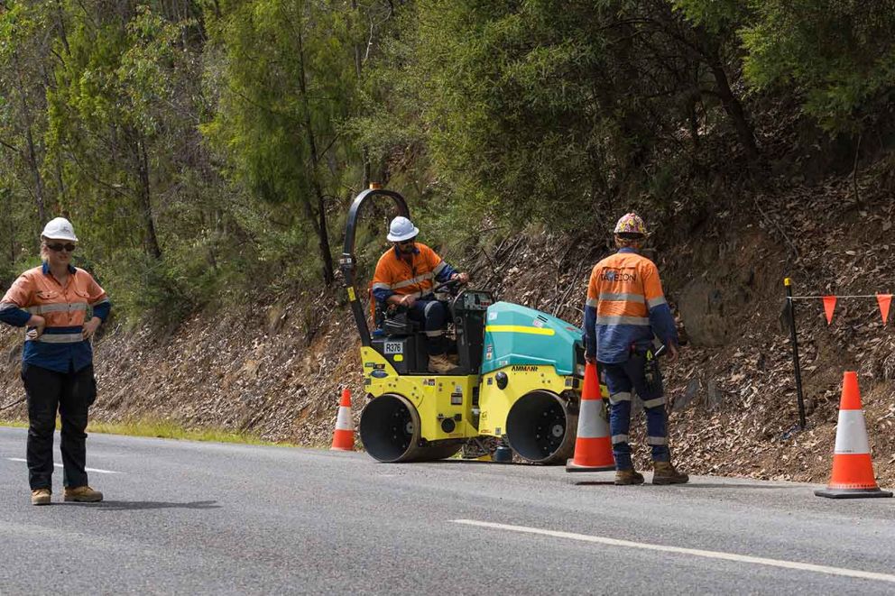 Crews working behind barriers to repair damaged road edge