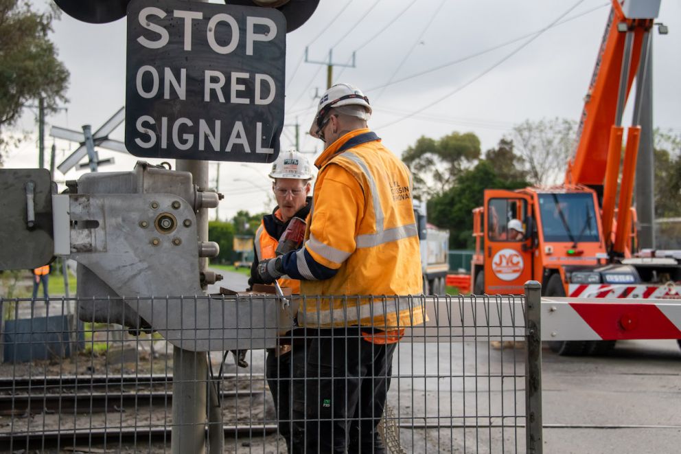 Two workers preparing the removal of the Racecourse Road boom gate