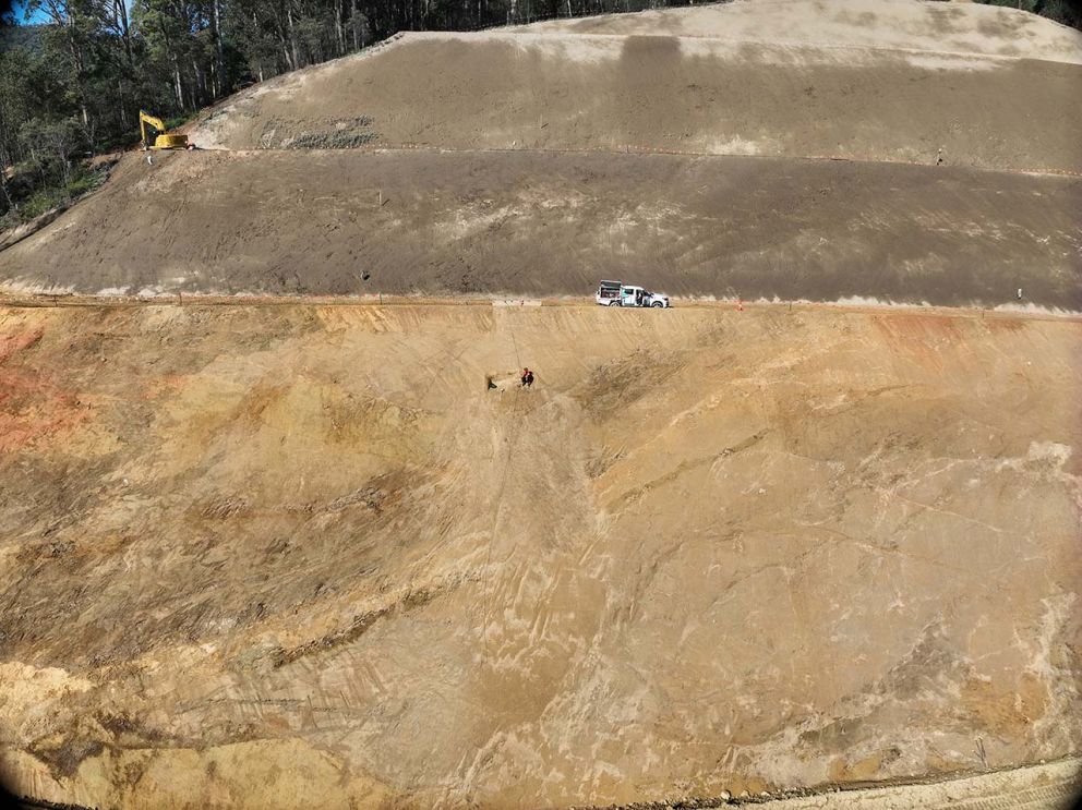 A crew member uses a rope and harness to inspect the face of the landslip