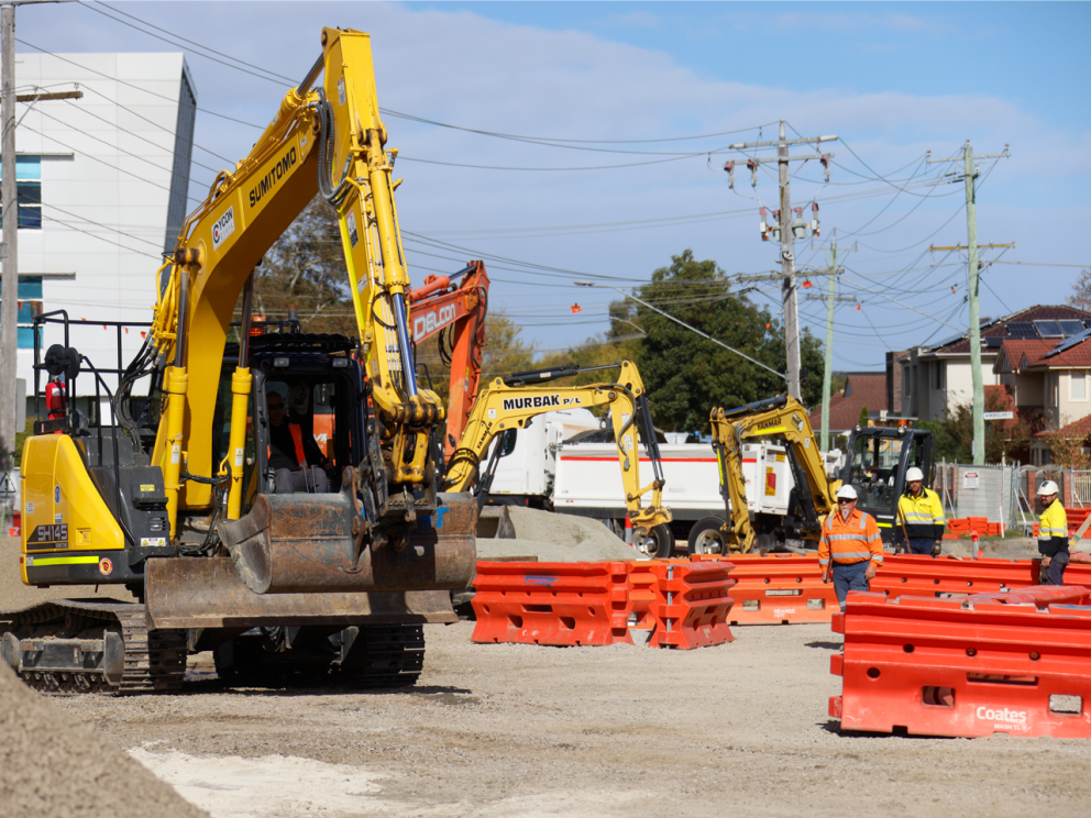 Image shows workers and operating machines in a construction zone in Glen Waverley