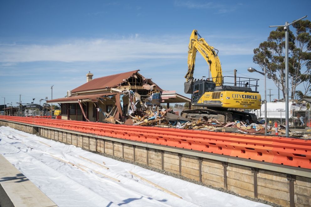 An excavator on the platform of Melton Station demolishes the station building