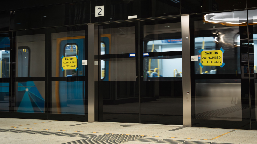 A train arriving at a Metro Tunnel Station behind closed platform screen doors