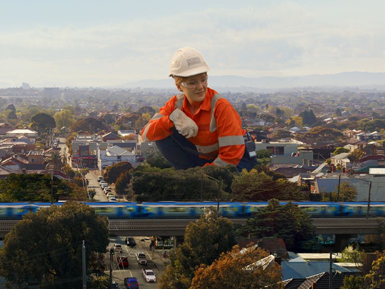 A giant construction works crouches over a train line.