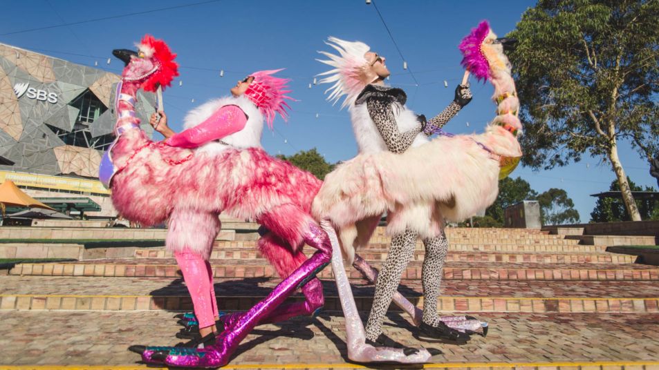 Two people dressed as white and pink emus