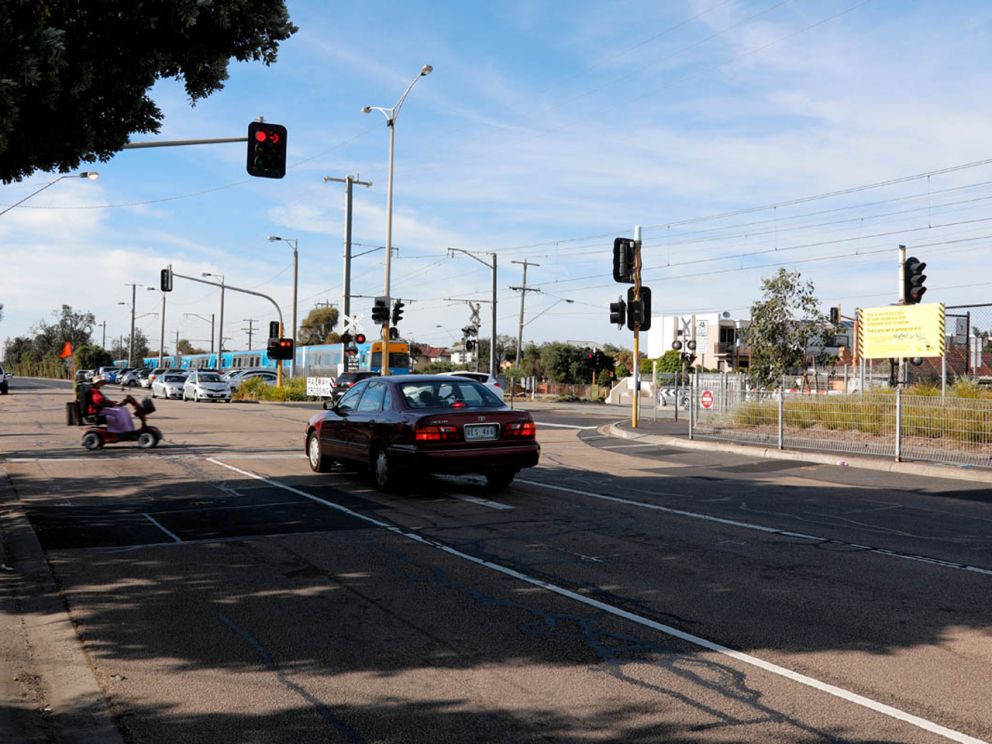 Pedestrian and car waiting at the Bondi Road level crossing before its removal