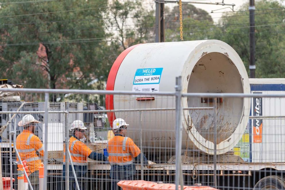 Workers standing next to a tunnel boring machine named 'Dora the Bora'
