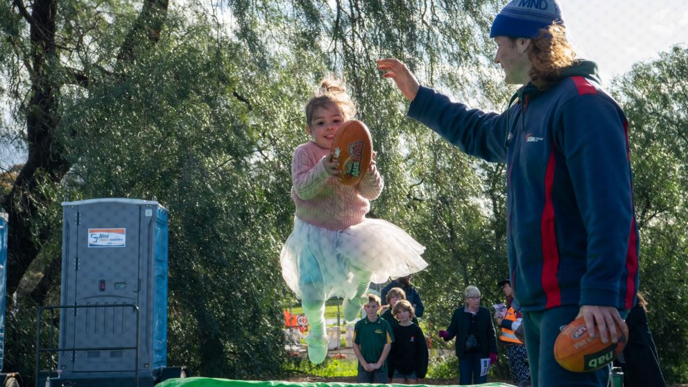 Shepparton community events girl in tutu catching footy