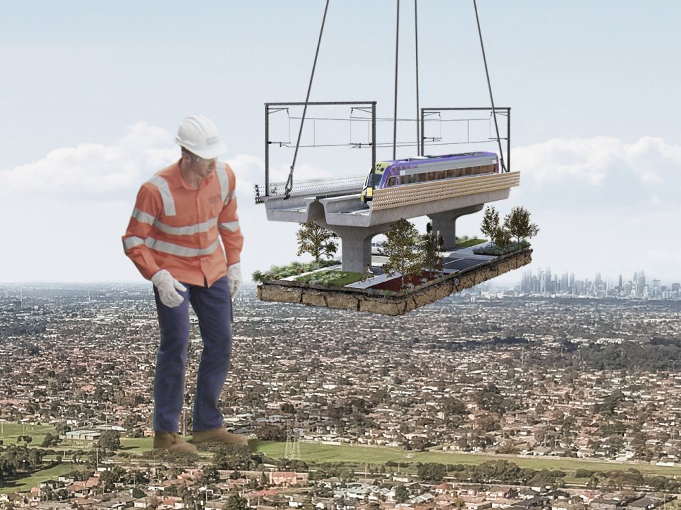 A giant construction worker lowers a giant V/Line train into place