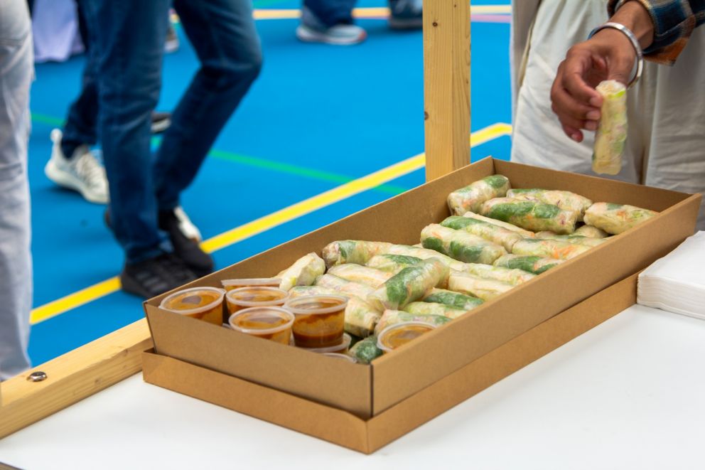 Image of a cardboard tray of rice paper rolls and brown hoisin sauce.