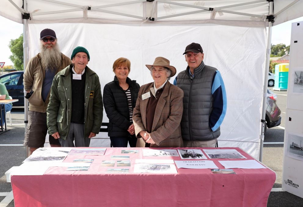 Group of people in a marquee smiling at the camera standing behind a table 