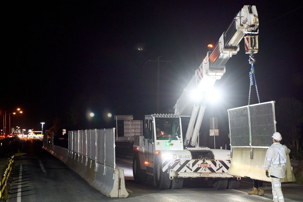 A franna crane placing barriers along the Western Port Highway median under the watchful eye of a safety spotter