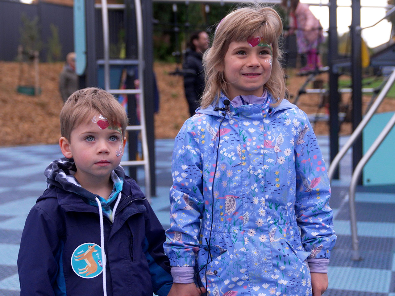 Two kids smiling for a photo in a park