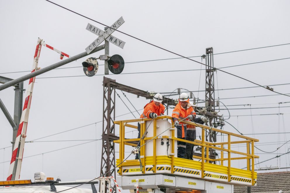 Workers on scissor lift above the level crossing