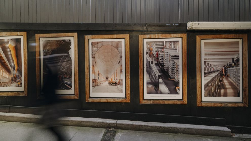 Image of blurred person walks past wooden frames containing images of construction.
