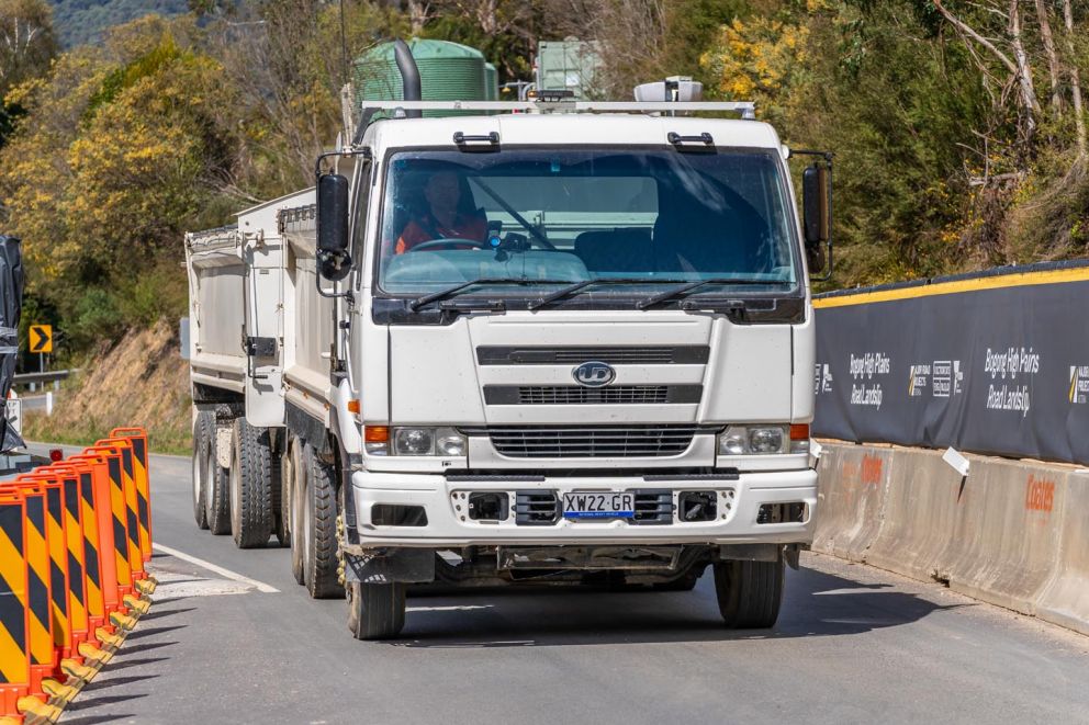 A truck passes through traffic management in front of the landslip