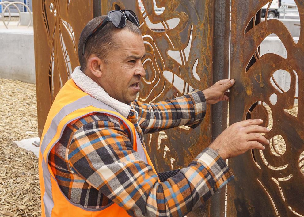 An indigenous man looking at aboriginal art panels