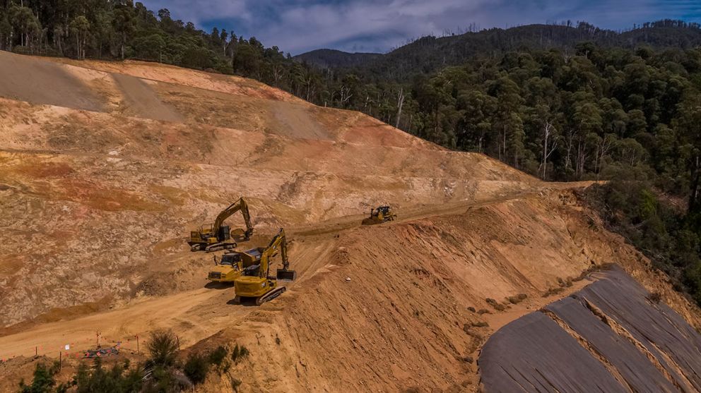 Construction vehicles work to clear material from the middle bench on the landslip