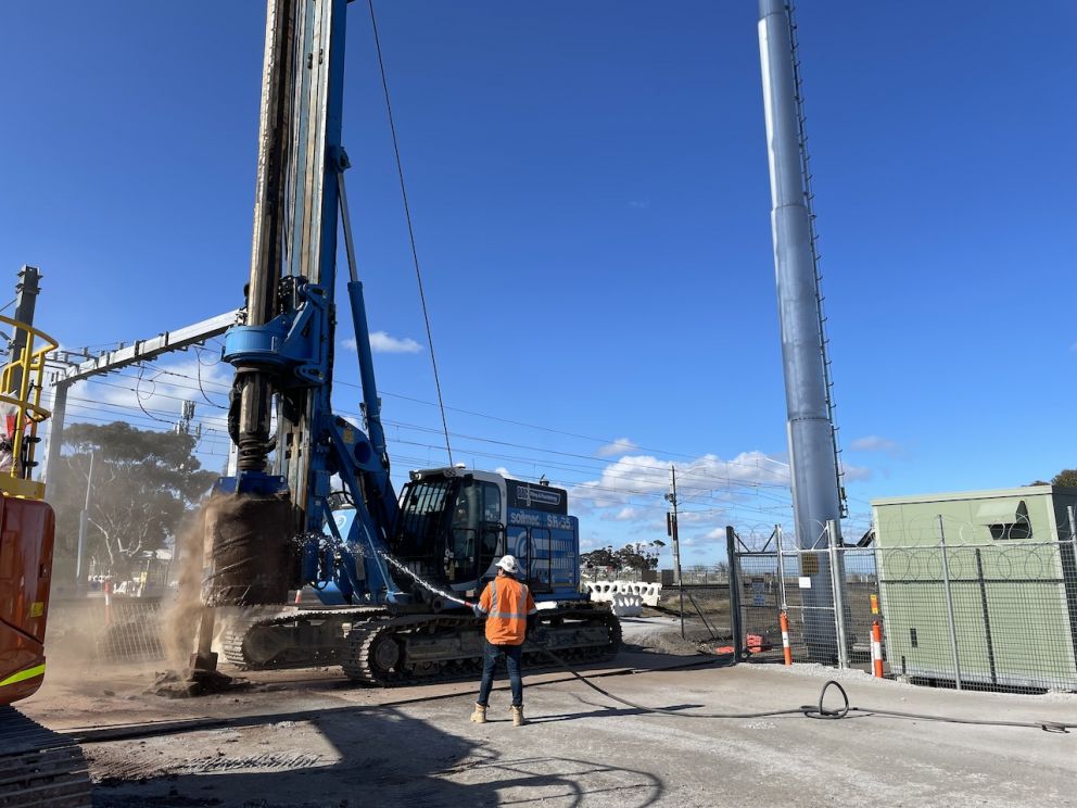 Worker hosing off the piling rig after it has drilled into the ground at Old Calder Highway