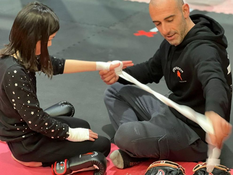 Coach strapping child's hand for boxing