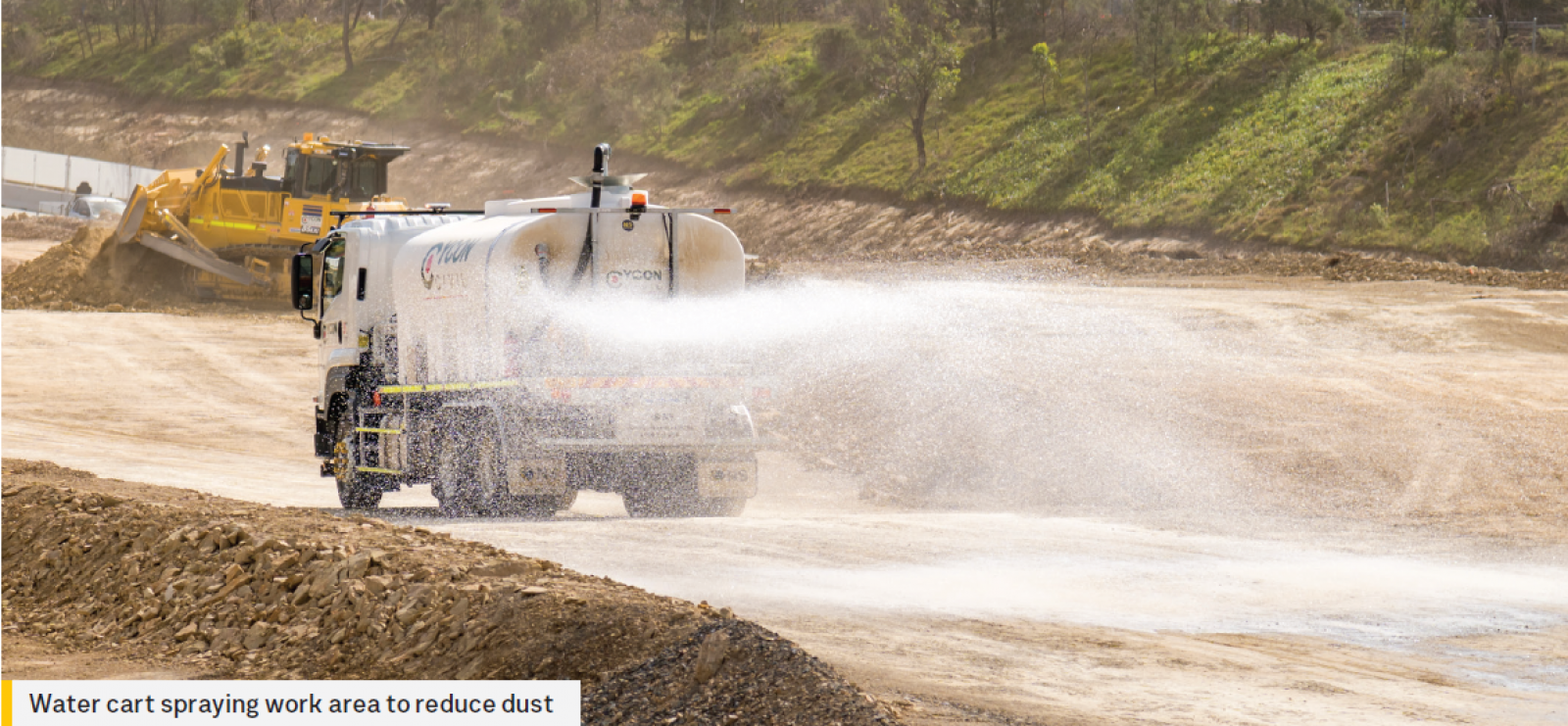 Water cart spraying work area to reduce dust