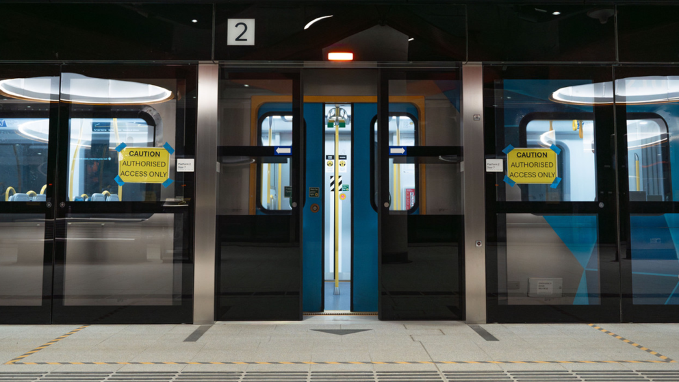 A train at a Metro Tunnel station with open doors and the platform screen doors closing