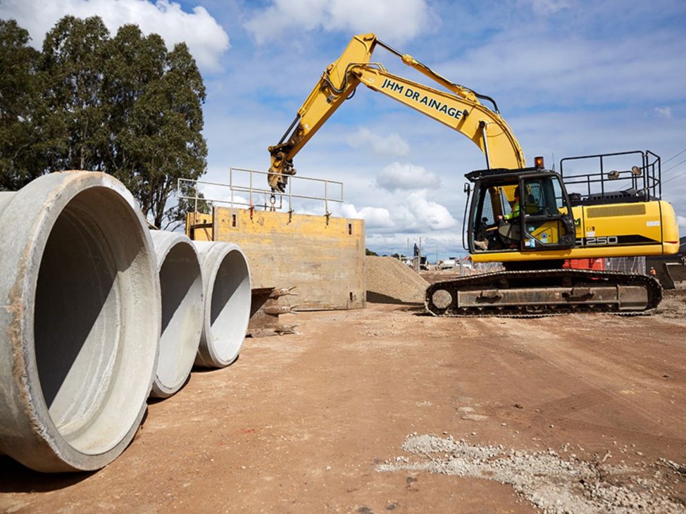 Image of a crane moving concrete mounds in the background. To the left of the image there concrete mounds