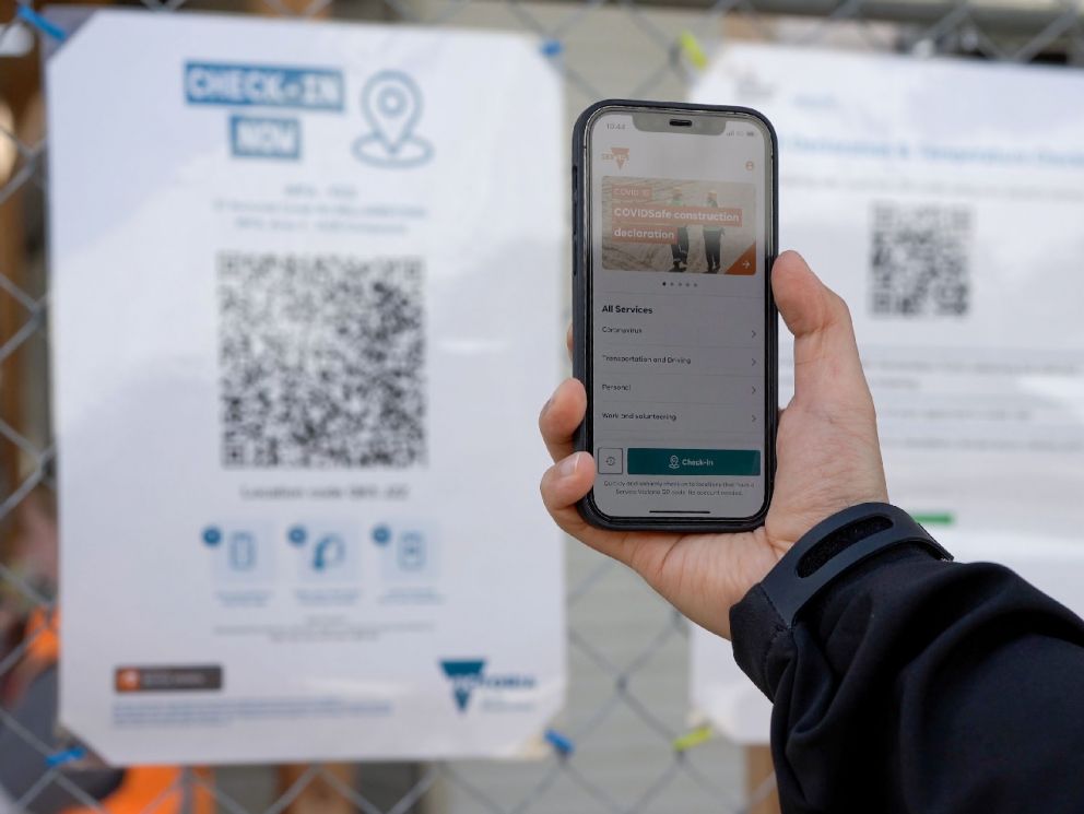 A hand hlding up a phone to use the QR code check in system onsite