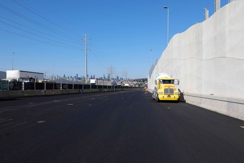 Photo of a cement truck and worker next to installed concrete noise wall panels